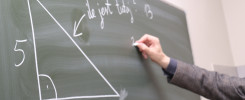 Trójkąt prostokątny z bokami 5 i 12. Ręka pisze kredą na tablicy. Kontekst: lekcja matematyki.