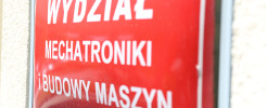 Czerwona tablica z białym napisem "WYDZIAŁ MECHATRONIKI I BUDOWY MASZYN".