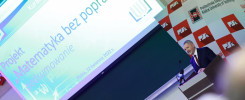 Mężczyzna w garniturze przemawia na tle ekranu z napisem "Projekt Matematyka bez poprawek" i logo Politechniki