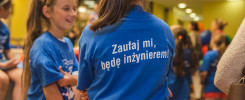 Dziewczynki w niebieskich koszulkach z napisem "Zaufaj mi, będę inżynierem!". Kontekst: wydarzenie edukacyjne.