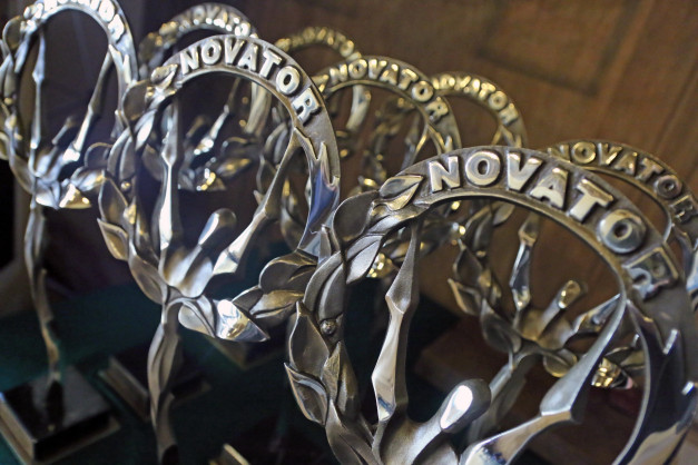 Metalowe statuetki z napisem "NOVATOR" ustawione w rzędzie.