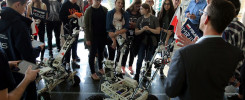 Grupa młodych ludzi ogląda roboty. W tle widać flagę Polski.