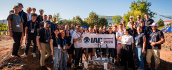 Grupa młodych ludzi pozuje z łazikiem i banerem "IAC POZNAN POLAND 2026".