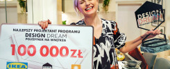 Kobieta trzyma tablicę z napisem "Najlepszy projektant programu DESIGN DREAM 100 000 zł" i statuetkę.