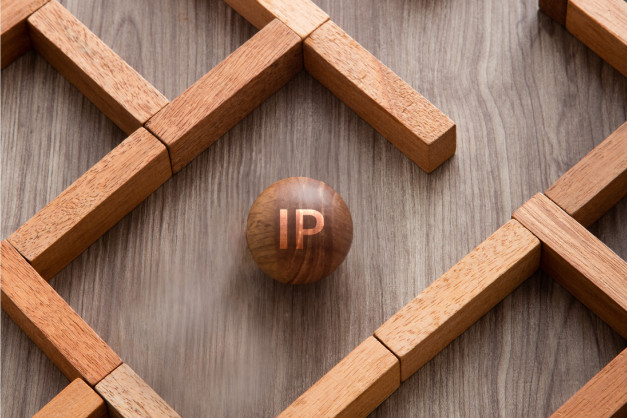Drewniana kula z literami "IP" w centrum labiryntu z klocków.