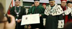 Uroczystość akademickia. Kluczowe obiekty: dyplom, togą, łańcuchy. Kontekst: ceremonia akademicka.