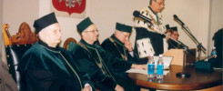 Uroczystość akademicka. W sali siedzą profesorowie w togach, jeden przemawia. Kontekst: ceremonia.