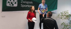 Dwie kobiety na podium, jedna z medalem i książką, druga z kaskiem. Tło: baner "Akademicki Związek Sportowy".