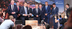 Mężczyźni w garniturach stoją przed ekranem z napisem "Świętokrzyski Kampus Laboratoryjny Głównego Urzędu Miar".