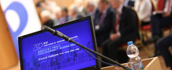 Monitor z napisem "XV Konferencja Naukowo-Techniczna", mikrofon, butelka wody. Kontekst: wydarzenie naukowe.