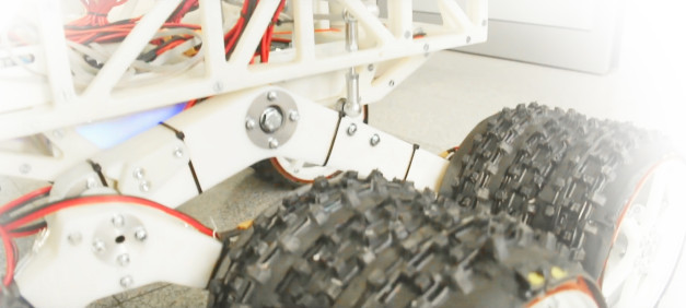 Biała rama robota z widocznymi przewodami i dwoma terenowymi kołami.
