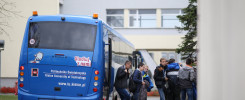 Niebieski autobus z napisem "Politechnika Świętokrzyska" i grupą młodych ludzi. Kontekst: wycieczka lub transport studencki.