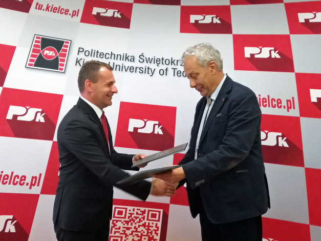 Dwóch mężczyzn w garniturach wymienia dokumenty. W tle logo Politechniki Świętokrzyskiej.