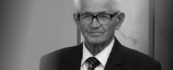 Czarno-białe ujęcie starszego mężczyzny w okularach, białej koszuli i krawacie.