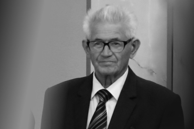 Czarno-białe ujęcie starszego mężczyzny w okularach, białej koszuli i krawacie.