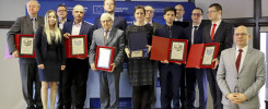 Grupa osób odbiera nagrody. W tle widoczny jest niebieski baner z logotypem UE.