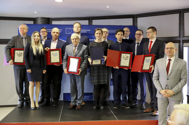 Grupa osób odbiera nagrody. W tle widoczny jest niebieski baner z logotypem UE.