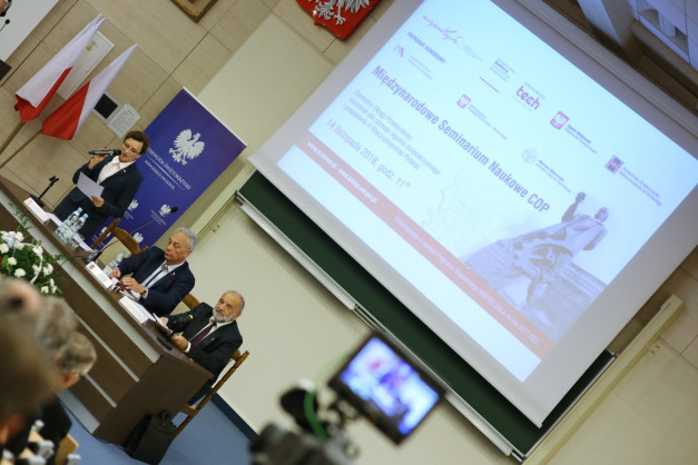 Kobieta przemawia na forum, obok siedzą mężczyźni. Kontekst: Międzynarodowe Seminarium Naukowe COP.